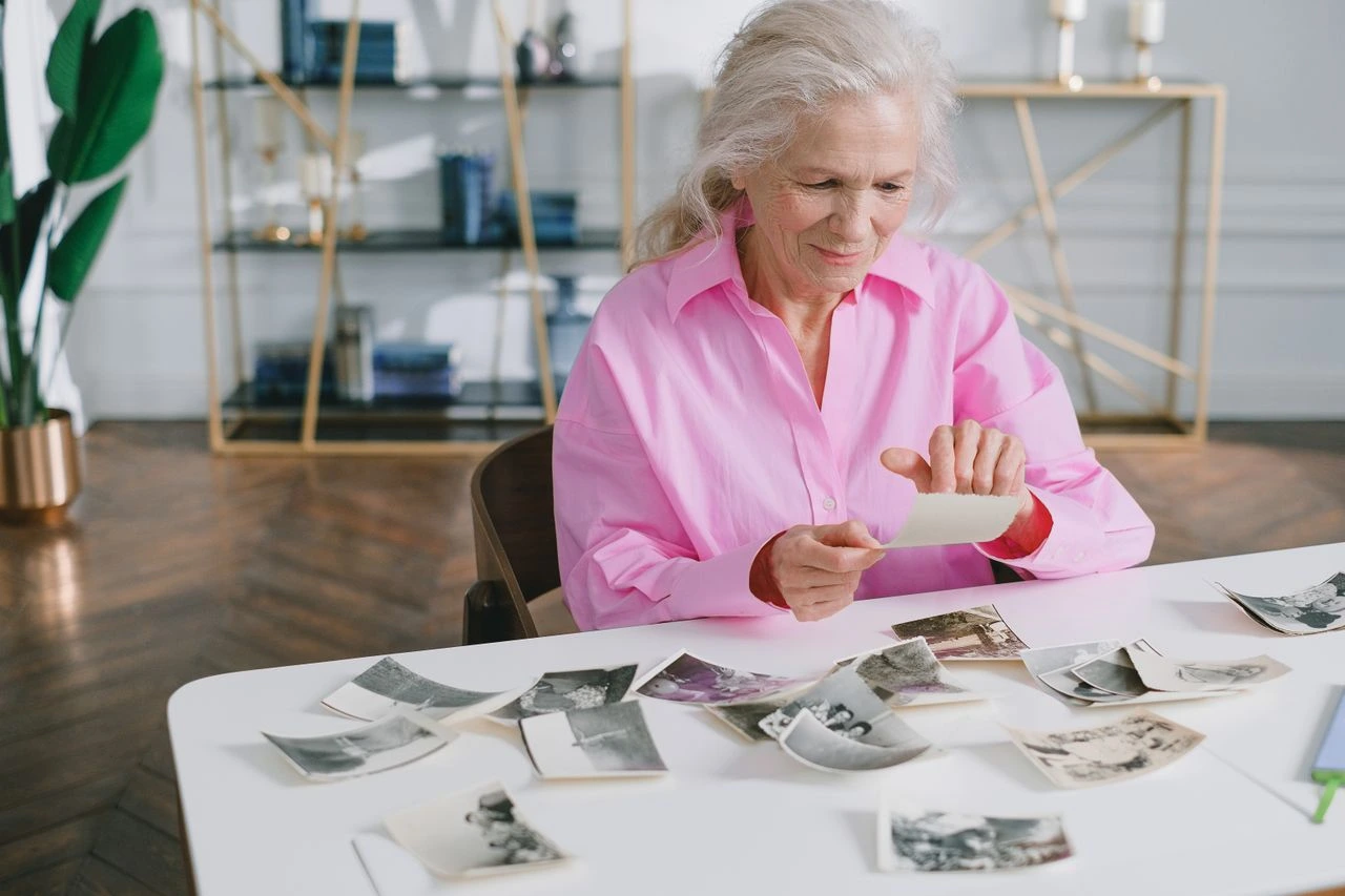 Une dame âgée regarde des photos de sa jeunesse en vue d’écrire sa biographie