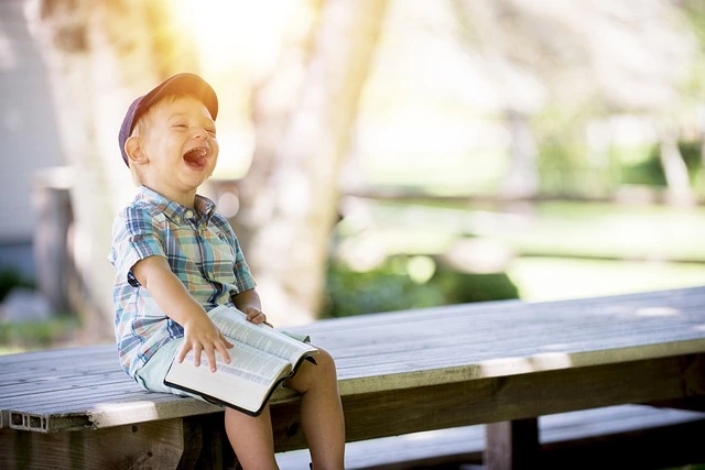 Un petit garçon éclate de rire en lisant une anecdote relatée dans la biographie de sa grand-mère